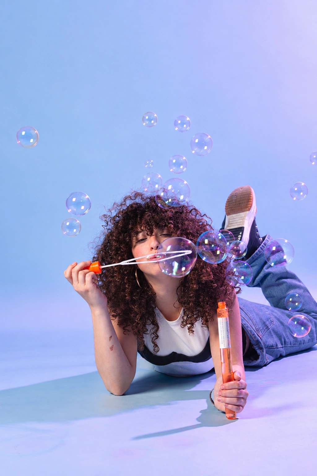 Galia in a playful studio portrait blowing soap bubbles